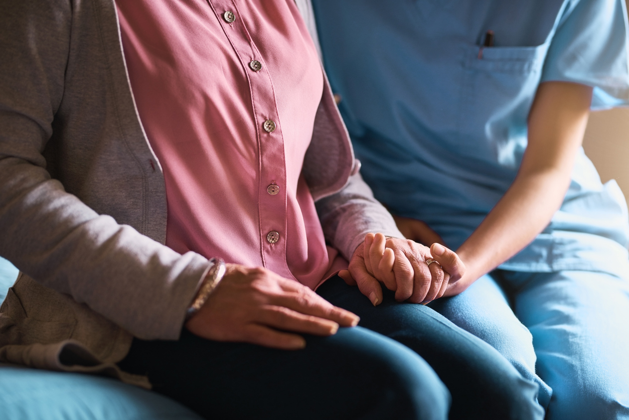 Senior care advisor and elderly woman holding hands, providing compassionate support and guidance.
